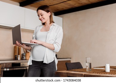 pregnant and happy freelancer using laptop at home - Shutterstock ID 1743084038