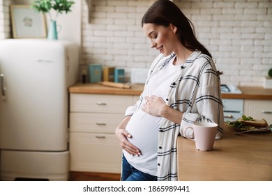 Pregnant happy nice woman smiling while having breakfast in home kitchen - Powered by Shutterstock