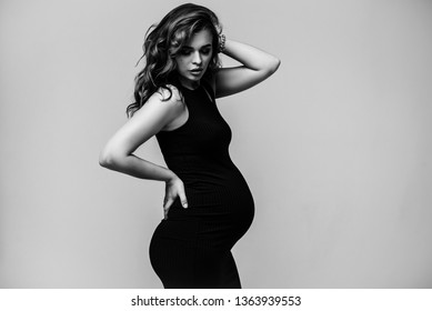 Pregnant happy Woman in black dress. Fashion shot in the studio on the background. Beautiful pregnant girl.