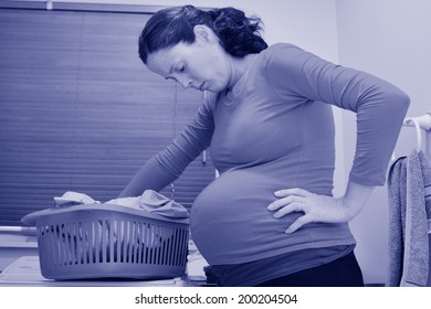 Pregnant Housewife Woman Doing Housework, Washing Family Clothes, During Pregnancy.Concept Photo Of Pregnancy, Pregnant Woman Lifestyle And Health Care. Crop Image - Copyspace (BW)