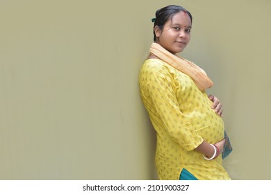 A pregnant Indian lady with a yellow dress and hands-on belly. Motherhood and pregnancy concept.