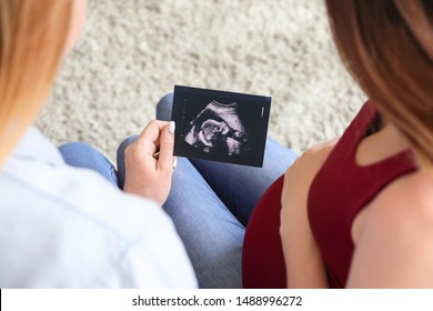 Pregnant Lesbian Couple With Sonogram Image At Home