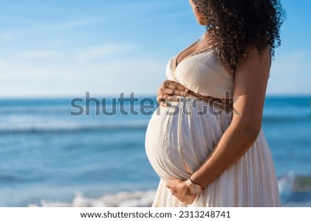 Pregnant maternity latin woman on the beach at sunset, maternity concept