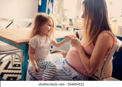 pregnant mother playing with toddler daughter on the kitchen, real life interior lifestyle