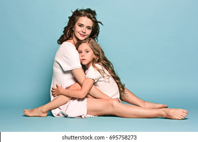 Pregnant Mother With Teen Daughter. Family Studio Portrait Over Blue Background