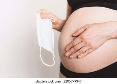 Pregnant Mother Use Face Mask Covering On Her Abdomen. Childbirth, Contractions With Face Mask During Quarantine. Afraid Spread Coronavirus Covid.