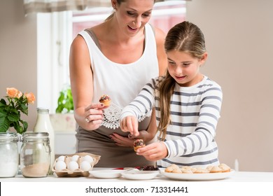 Pregnant Mum And Her Little Daughter Baking Together And Decorating The Cupcakes