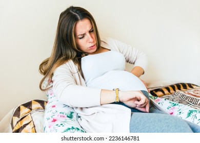 Pregnant pain contractions. Pregnant woman watching clock, holding baby belly. Childbirth time, contractions pain. Pregnancy, medicine health care concept - Shutterstock ID 2236146781