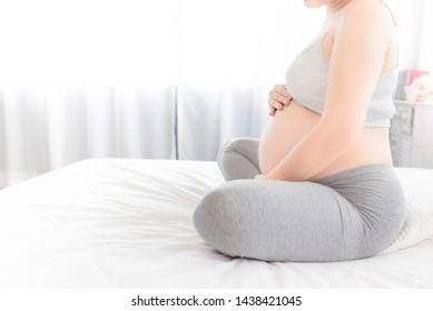 Pregnant People Sitting On White Bed, She  Use Her Hand Touch On Her Abdomen, She Feeling Love And Care Her Daughter, Pregnancy Health Care Promotion