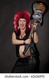 Pregnant Sexy Woman Acting As Rock Star With Red Rumpled Wig, Leather Clothes And Electrical Guitar. Concept Image For Fun And Extreme During Pregnancy. Studio Shot. See More In My Portfolio