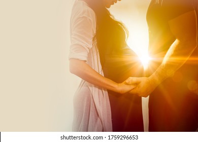 Pregnant wife couple lover standing holding hand care together wtih sunshine for always stand by me and be good love forever concept.