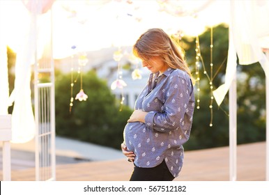 Pregnant woman against the backdrop of the city in the evening