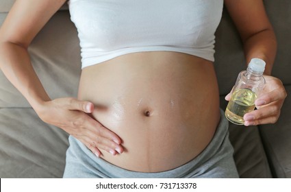 Pregnant woman applying cream at her belly for prevention of stretch marks on the skin