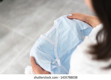 pregnant woman with baby clothes - Shutterstock ID 1435788038