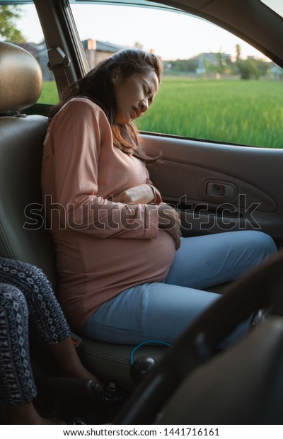 pregnant woman belly ache during trip on car\
holding her tummy