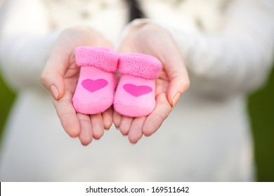 Pregnant woman belly holding pink baby booties, expecting girl. Healthy pregnancy.  - Powered by Shutterstock