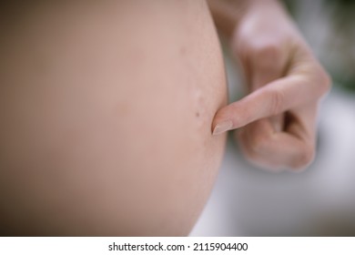 Pregnant Woman Belly. Pregnancy Concept. Isolated On Black Background. Pregnant Tummy Close Up With Finger Pointing On Belly Button.