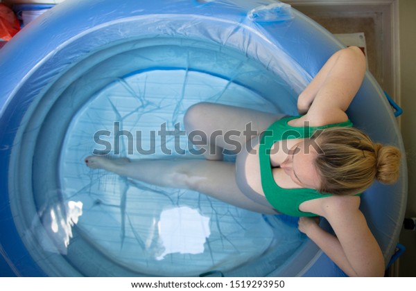 A pregnant woman in a birthing pool during a\
natural home birth