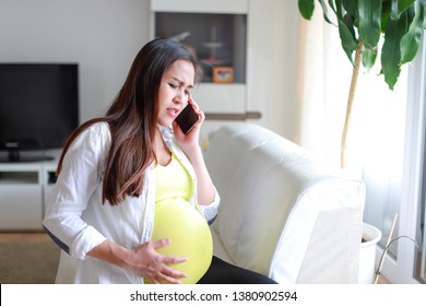 Pregnant woman calling to doctor or emergency for help she have pain on last trimester. Asian pregnancy worried talking on phone.