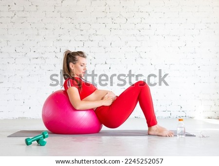 Pregnant woman doing exercise on the floor with a fit ball.