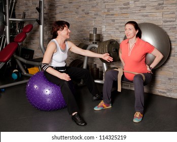 A pregnant woman doing exercises using fitness ball with her personal trainer