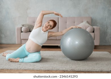 Pregnant woman doing side bends with a fitness ball at home.