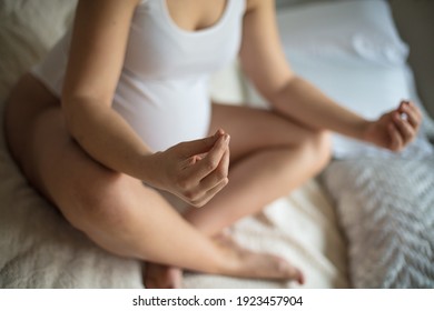 Pregnant Woman Doing Yoga Exercise On Bed. Focus Is On Hand. Close Up. 