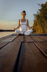 Pregnant Woman Doing Yoga At Lake During Sunset.