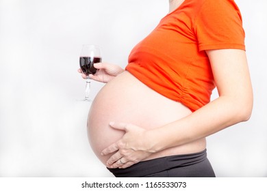 Pregnant woman drinking alcohol (red wine) during pregnancy. Concept photo of pregnancy, pregnant woman lifestyle and health care. With copyspace