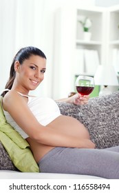 pregnant woman drinking glass of  wine at home