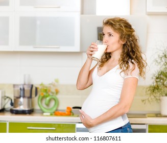 Pregnant Woman Drinking Milk At Kitchen