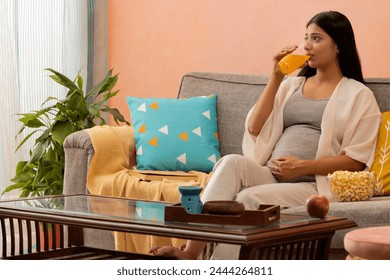 Pregnant woman drinking orange juice and relaxing at home - Powered by Shutterstock