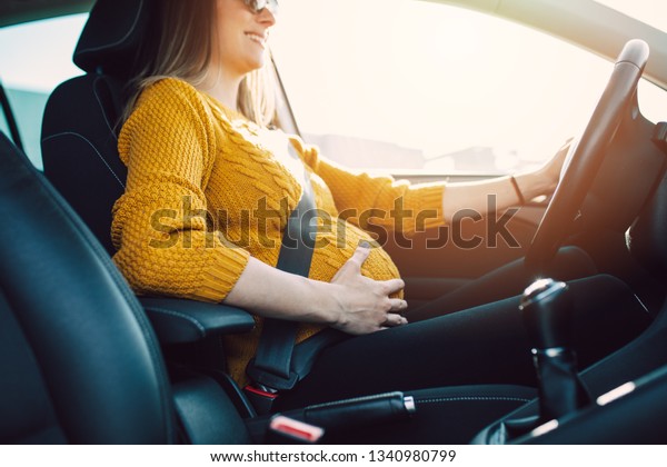 Pregnant\
woman driving with safety belt on in the\
car.