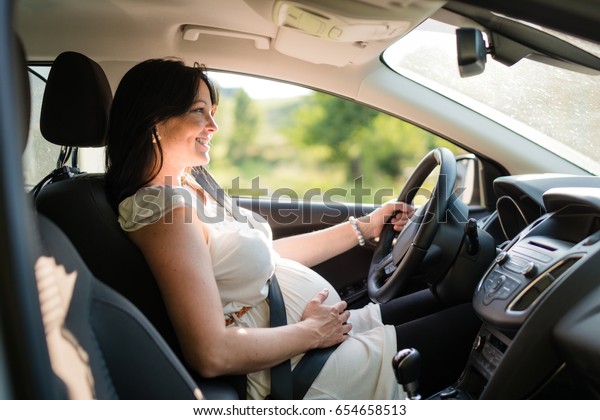 Pregnant\
woman driving with safety belt on in the\
car