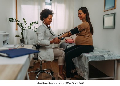 A Pregnant Woman During A Routine Check Up With Her Doctor. Doctor Is Measuring Temperature To Her