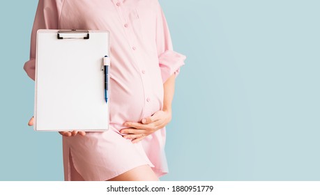 Pregnant woman with empty white paper as medical card, agreement blank. Concept of signing vaccination contract, work paper, writing birth plan. Healthcare checkup during pregnancy. Template for text.