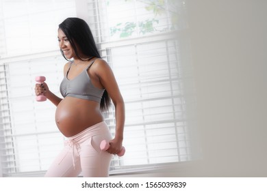 A Pregnant Woman Exercises By Lifting Weights At Home