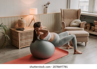 Pregnant woman exercising with fit ball at home, making squats with fitball. - Powered by Shutterstock