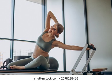 Pregnant Woman Exercising With The Help Of Reformer On Pilates Class