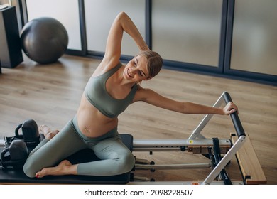 Pregnant Woman Exercising With The Help Of Reformer On Pilates Class