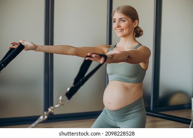 Pregnant Woman Exercising With The Help Of Reformer On Pilates Class