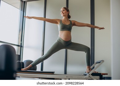 Pregnant Woman Exercising With The Help Of Reformer On Pilates Class