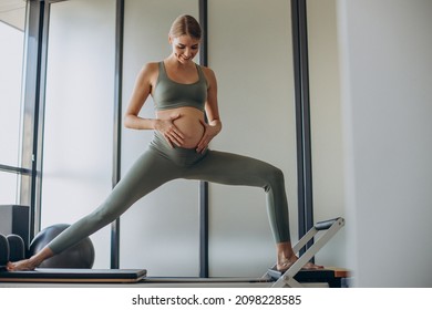 Pregnant Woman Exercising With The Help Of Reformer On Pilates Class