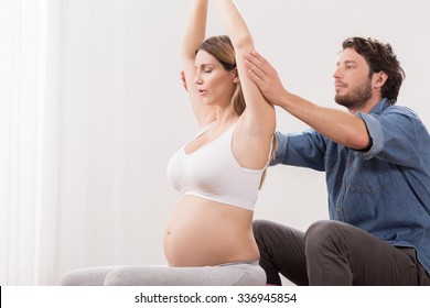 Pregnant woman exercising with physiotherapist in birthing school - Powered by Shutterstock