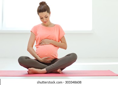 Pregnant woman exercising yoga on the mat