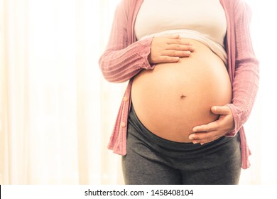 Mujer embarazada que se siente feliz en casa mientras cuida a su hijo. La joven que espera que su madre tenga un bebé en el vientre embarazada. Atención prenatal de maternidad y concepto de embarazo de la mujer.