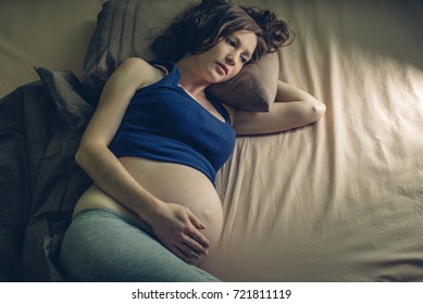 Pregnant Woman Feeling Pain In Her Belly Lying In Bed With Insomnia At Night. The Concept Of Pregnancy And Health