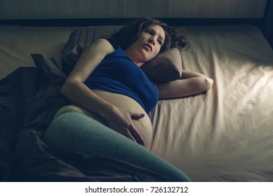 Pregnant Woman Feeling Pain In Her Belly Lying In Bed With Insomnia At Night. The Concept Of Pregnancy And Health