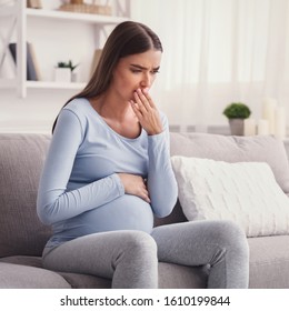 Pregnant Woman Feeling Sick Having Pregnancy Morning Sickness Sitting On Couch At Home