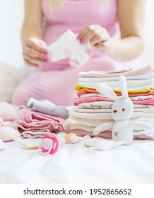 A Pregnant Woman Is Folding Baby Things. Selective Focus. People.